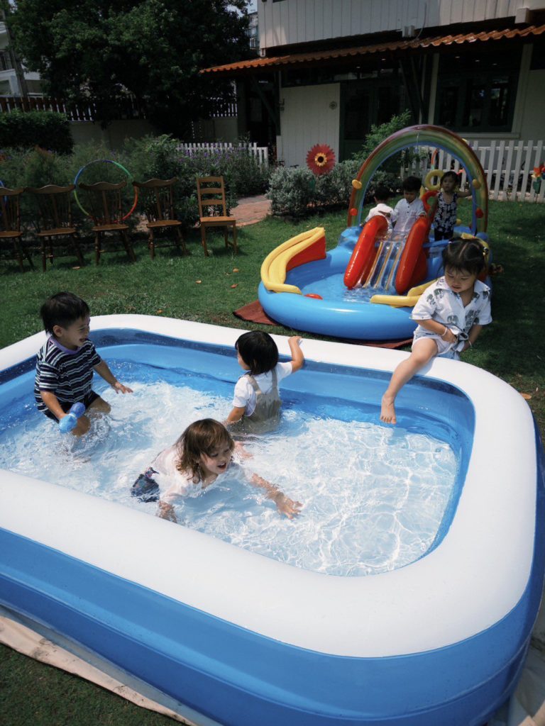 Toddlers splashing in water during a sensory play session at Firefly Forest School in Bangkok."

