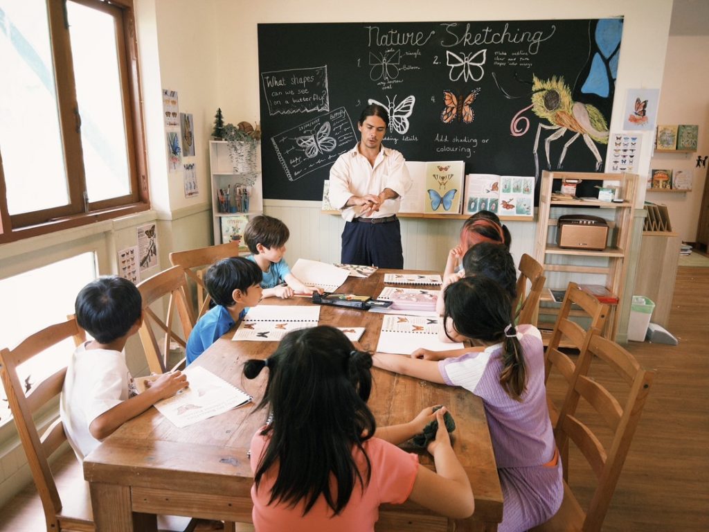 Children learning how to draw a butterfly while learning its name in Thai during a bilingual preschool activity at Firefly Forest School.

